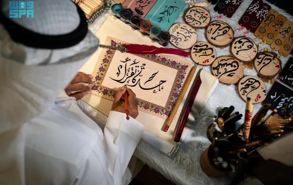 خطاط سعودي يرسم شعار معرض جدة للكتاب "جدة تقرأ" - الصورة من وكالة الأنباء السعودية "واس"