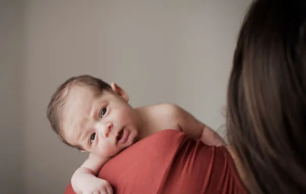 صورة لأم تحمل رضيعها المتألم