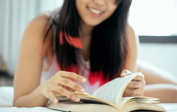 فتاة تقرأ كتابا وهي تبتسم بسعادة