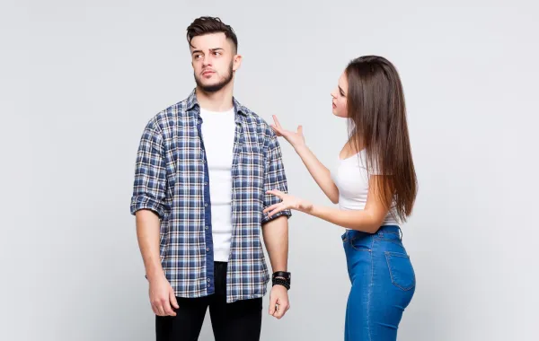 زوج يبدو مستاء وزوجته تعاتبه وهي تضع يدها على كتفه   