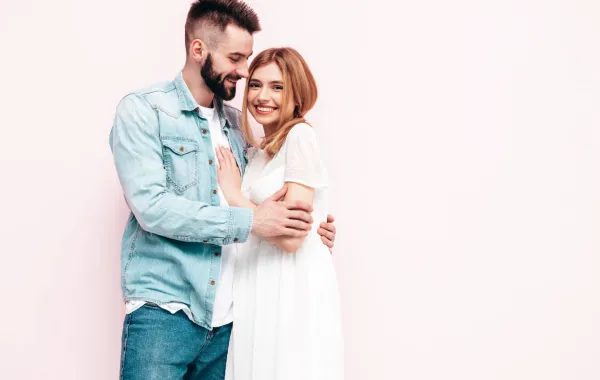 زوج يحتضن زوجته بمحبة وهي مشرقة وتبتسم بسعادة