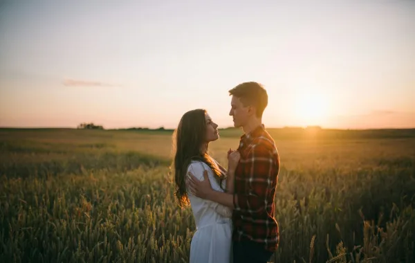 زوج يحتضن زوجته في يوم الحب يحيط بهما غروب الشمس