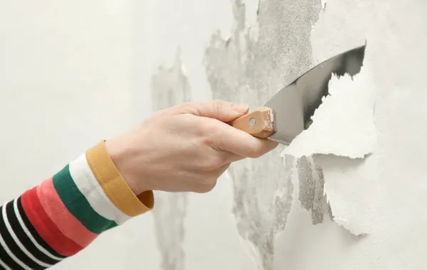 امرأة تزيل الطلاء المتقشر في المنزل