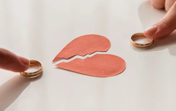 زوجان بينهما قلب مكسور كل منهما يمسك خاتمه علامة الانفصال