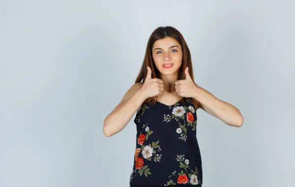 فتاة ترفع إبهامي يديها بسعادة، معبّرةً عن الفرح