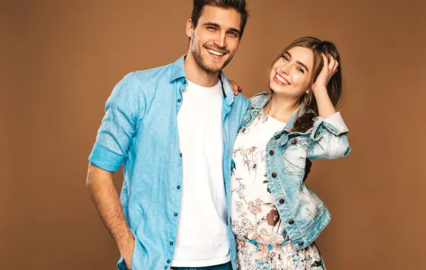 زوجان سعيدان مبتسمان والزوج يضع يده على وسط زوجته بمودة  