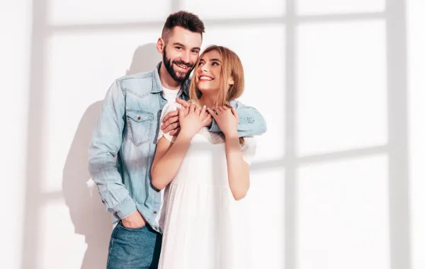 زوج يحتضن ظهر زوجته وهي تضحك بسعادة   