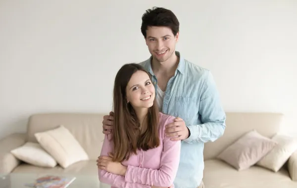 زوج يحتضن كتف زوجته ويبتسم بمحبة وهي تبتسم بسعادة   