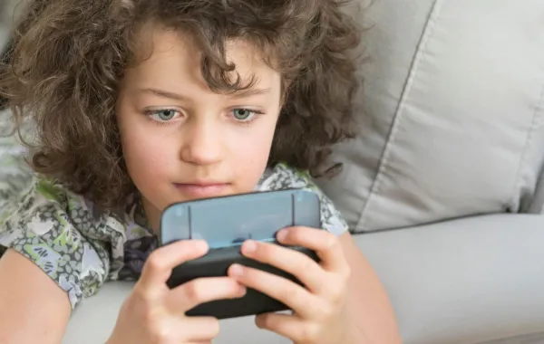 صورة طفلة تنظر إلى الموبايل