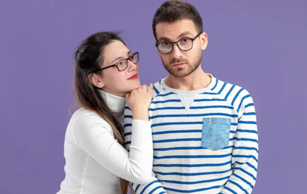 زوجة تضع ذقنها على كتف زوجها وتنظر لعينيه بذكاء  