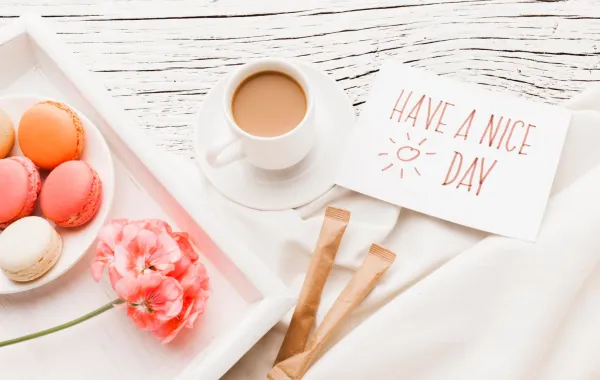 فنجان من القهوة حلوى وزهور وعبارة صباح الخير