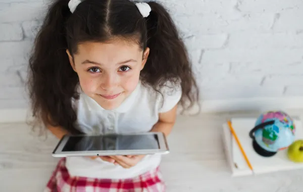 صورة لطفلة تحمل جهازاً رقمياً