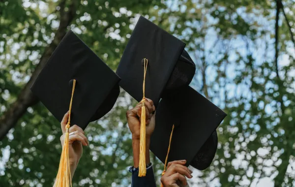 مجموعة من الخريجين يرفعون قبعة التخرج لاعلى 