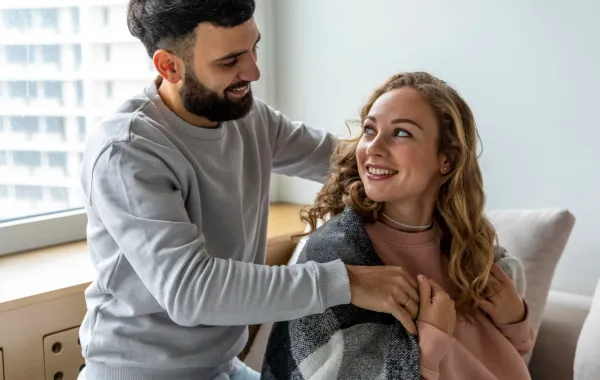 زوج يغطي كتفي زوجته بوشاح لتدفئتها  علامة على اهتمامه بها 