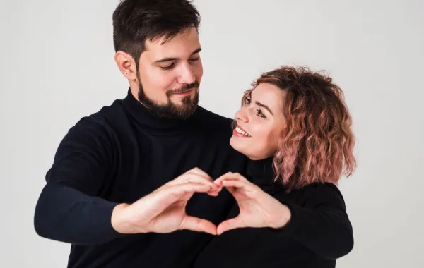 خطيبان يكونان معاً بيديهما شكل قلب ويبتسمان بسعادة   