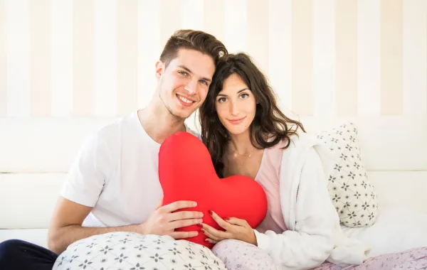 زوجان يمسكان قلباً أحمر ويبتسمان