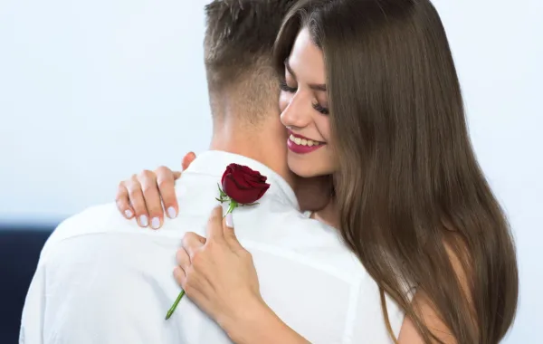 زوج أهدى لزوجته زهرة حمراء وهي تحتضنه بمحبة