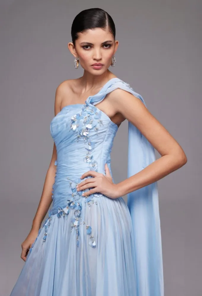 الفستان الأزرق المطرَّز باللؤلؤ والكريستال بقصة كتف واحدة -الصورة من نور الظاهري 