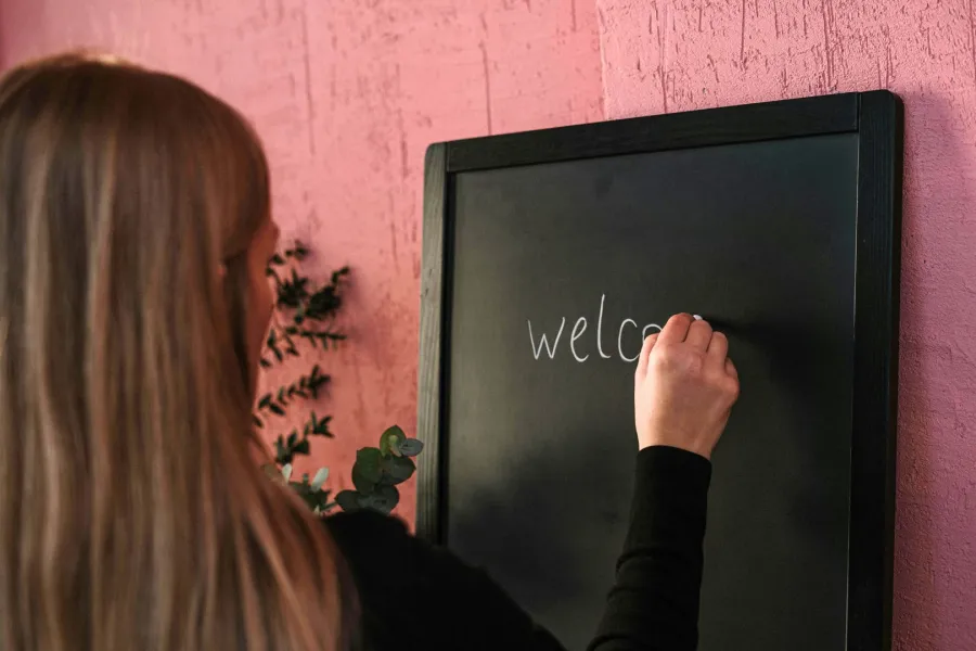 معلمة تكتب عبارة  ترحيبية بالطلبة   