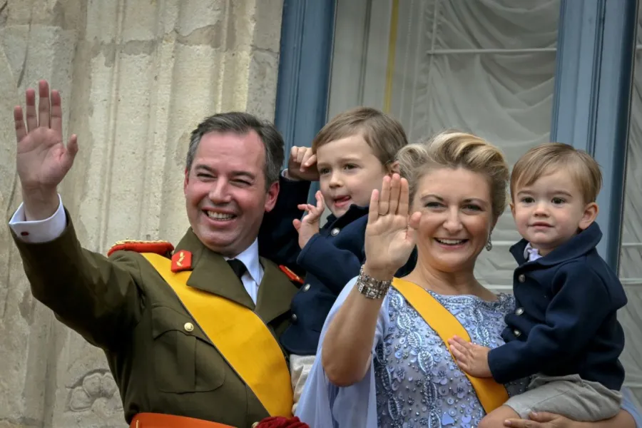 الدوق الأكبر غيوم والدوقة ستيفاني يحملان ابنيهما تشارلز وفرانسوا من شرفة القصر الدوقي الكبير (Grand Duke Guillaume and Duchess Stephanie hold their sons Charles and Francois from the balcony of the Grand Ducal Palace). مصدر الصورة: NICOLAS TUCAT / AFP