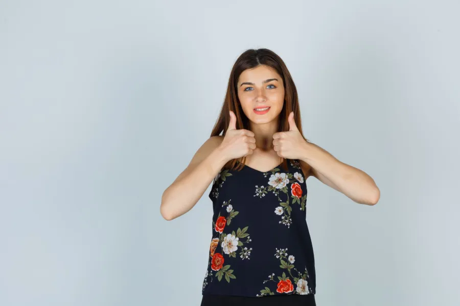فتاة ترفع إبهامي يديها بسعادة، معبّرةً عن الفرح